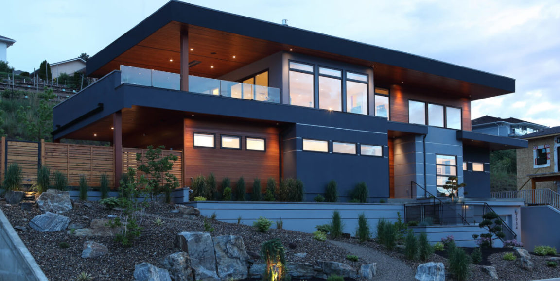 Modern custom home built by Keith Construction with large windows, wood and metal exterior, and landscaped hillside in Vernon, BC