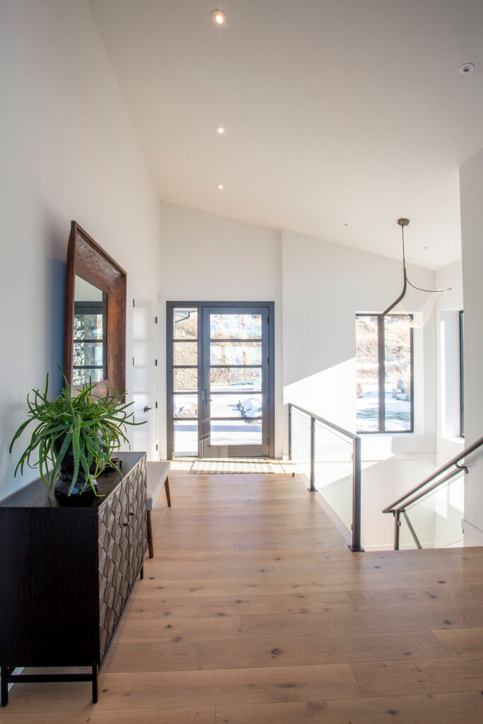 Photo of sunlit glass front door, entry and stairwell.