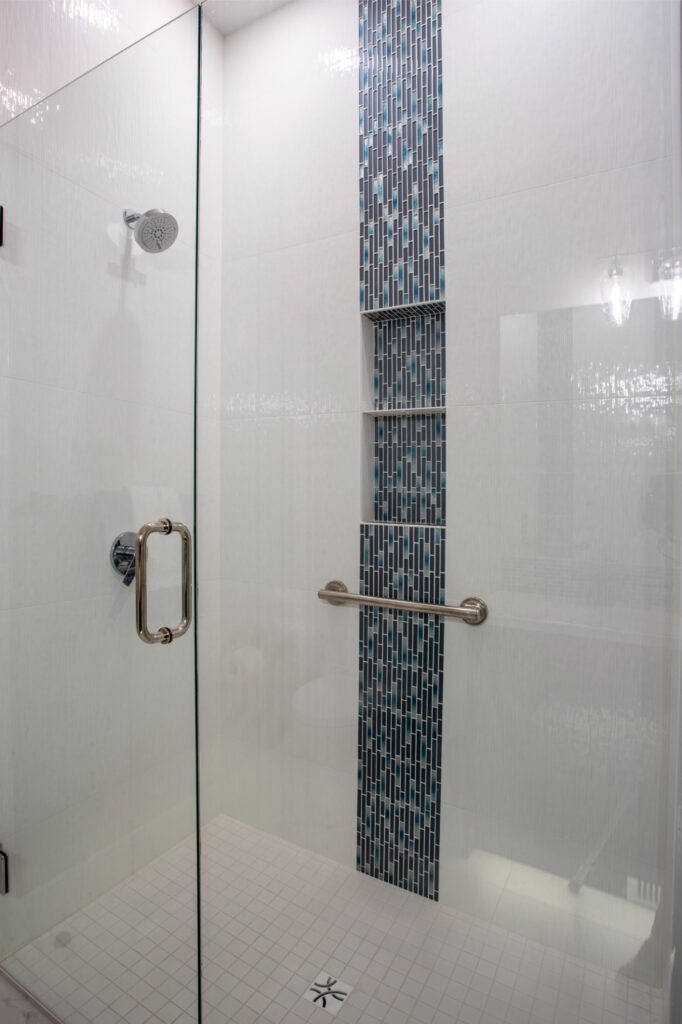 Photo of walk-in white tiled glass shower with black, turquoise accent tiles.