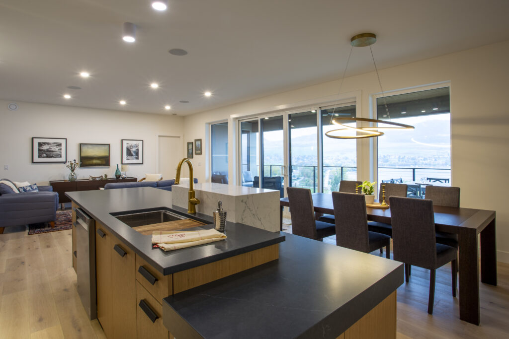 Modern kitchen with black countertop island, dining area, and large sliding glass doors.
