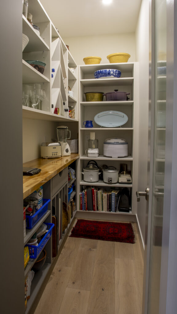Pantry with wooden shelves, appliances, and various kitchen items neatly organized.