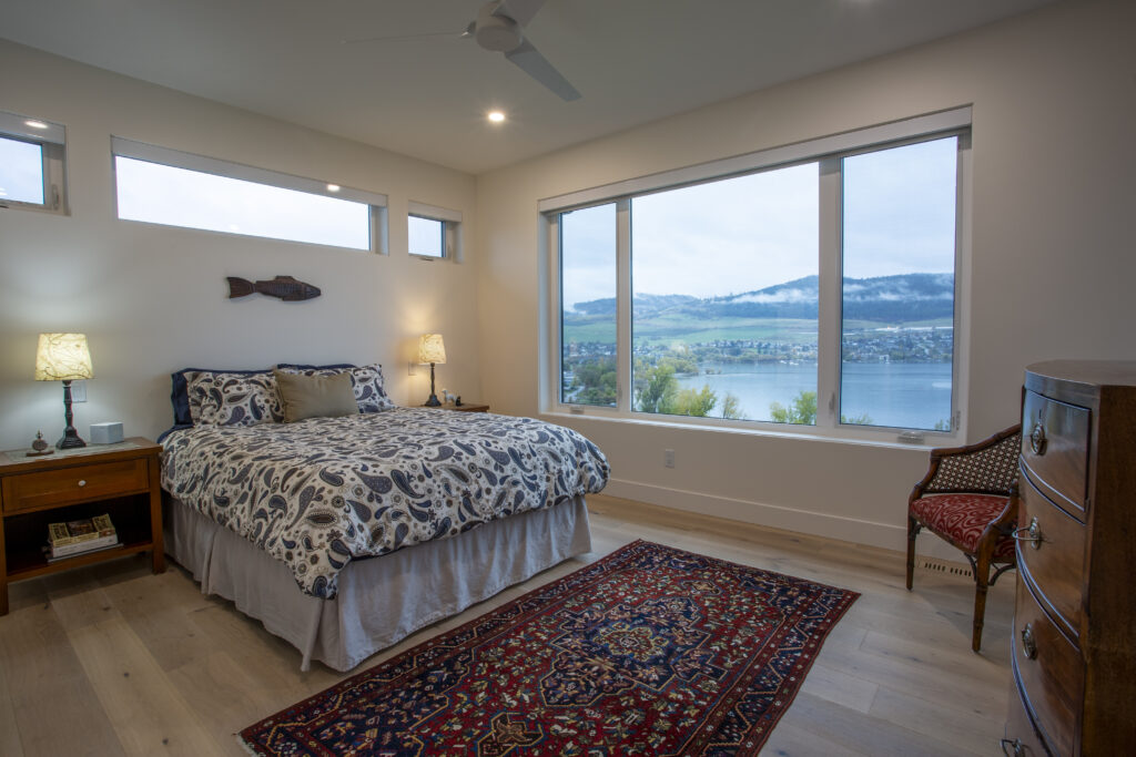Bedroom with large windows, colorful rug, and a view of the lake.