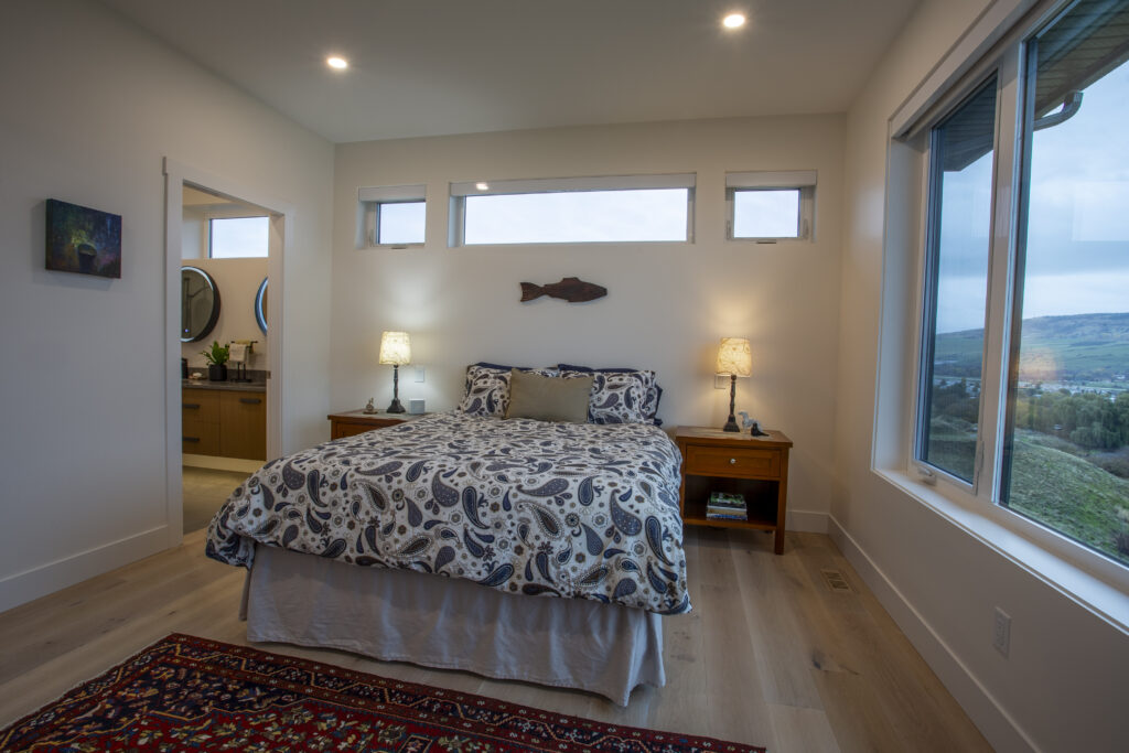 Bedroom with large windows, colorful rug, and a view of the lake.