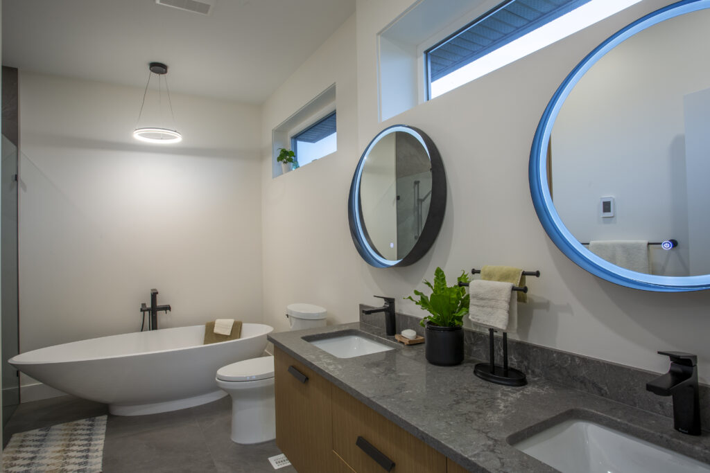 Bathroom with dual sinks, round mirrors, and a freestanding bathtub.