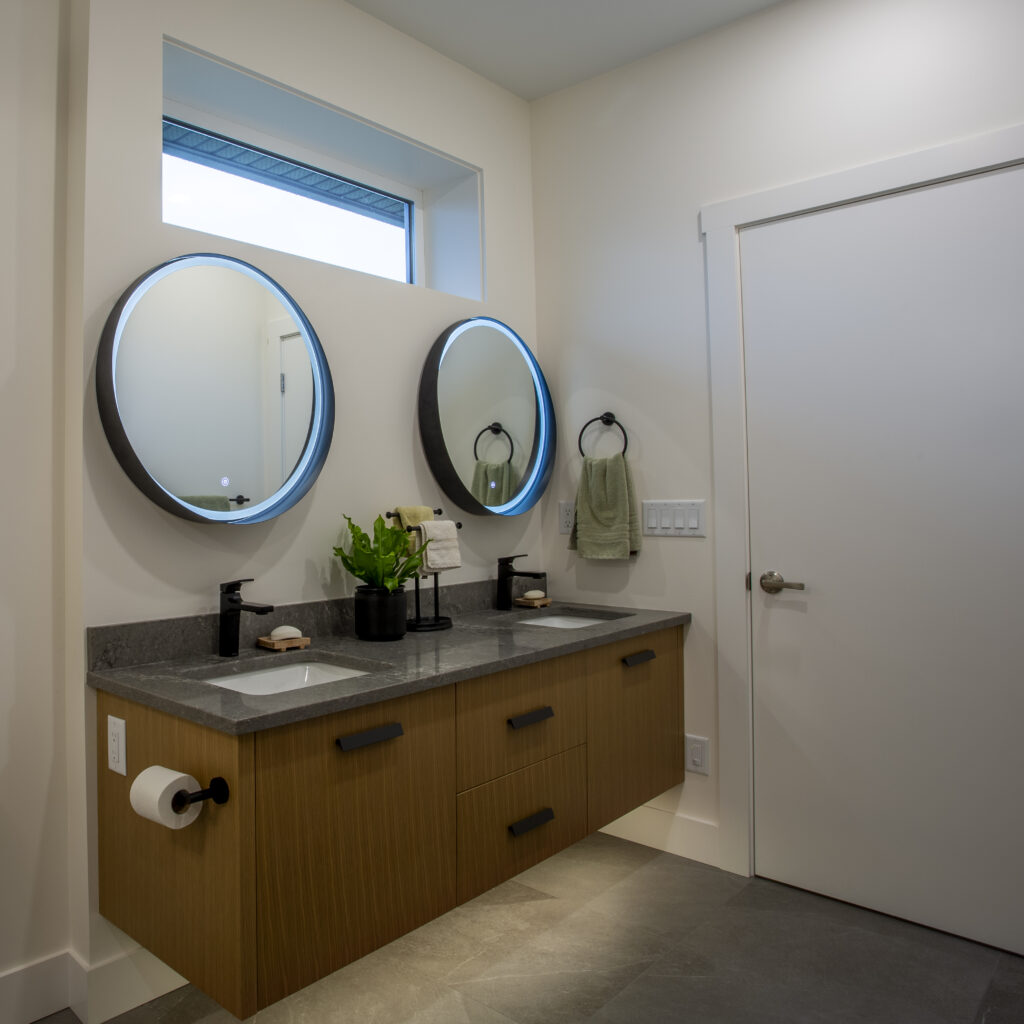 Bathroom with dual sinks, round mirrors, and a freestanding bathtub.