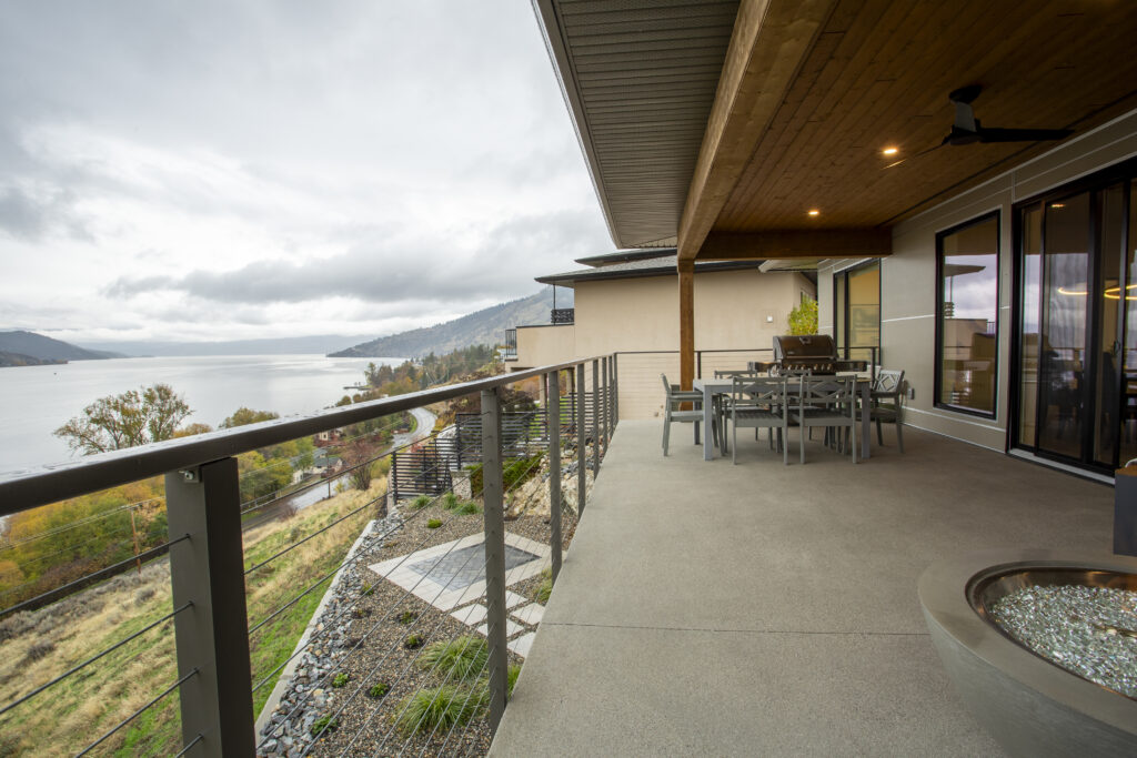 Covered outdoor patio with a dining table and a view of the lake and hills.