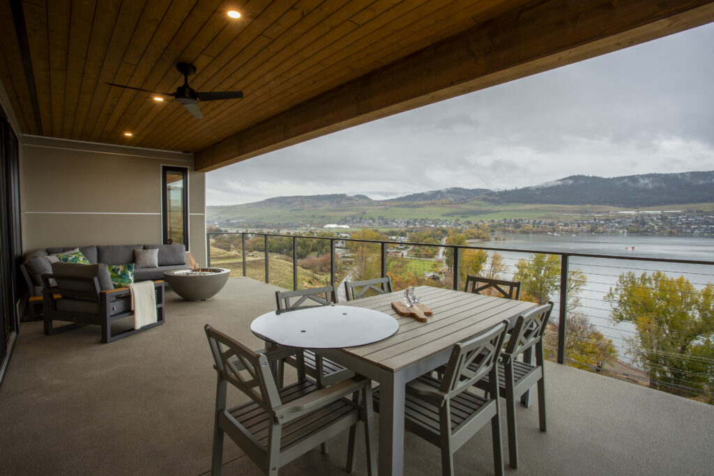 Covered outdoor patio with a dining table and a view of the lake and hills.