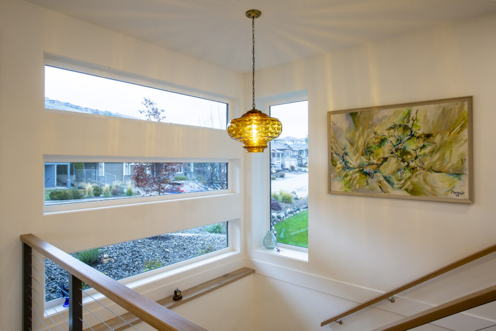 Staircase landing with large windows, pendant light, and framed artwork.