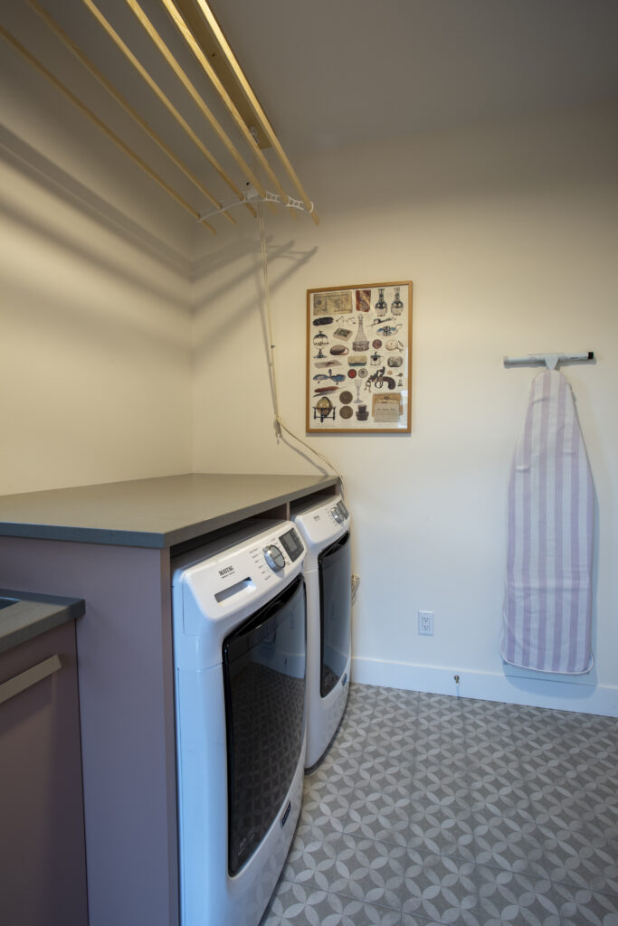 Laundry room with a washer and dryer, wooden countertop, and drying rack.
