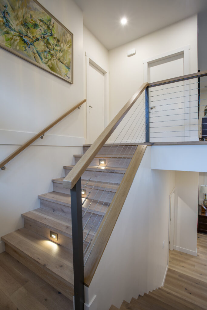 Staircase with wooden steps, metal railing, and recessed lighting.
