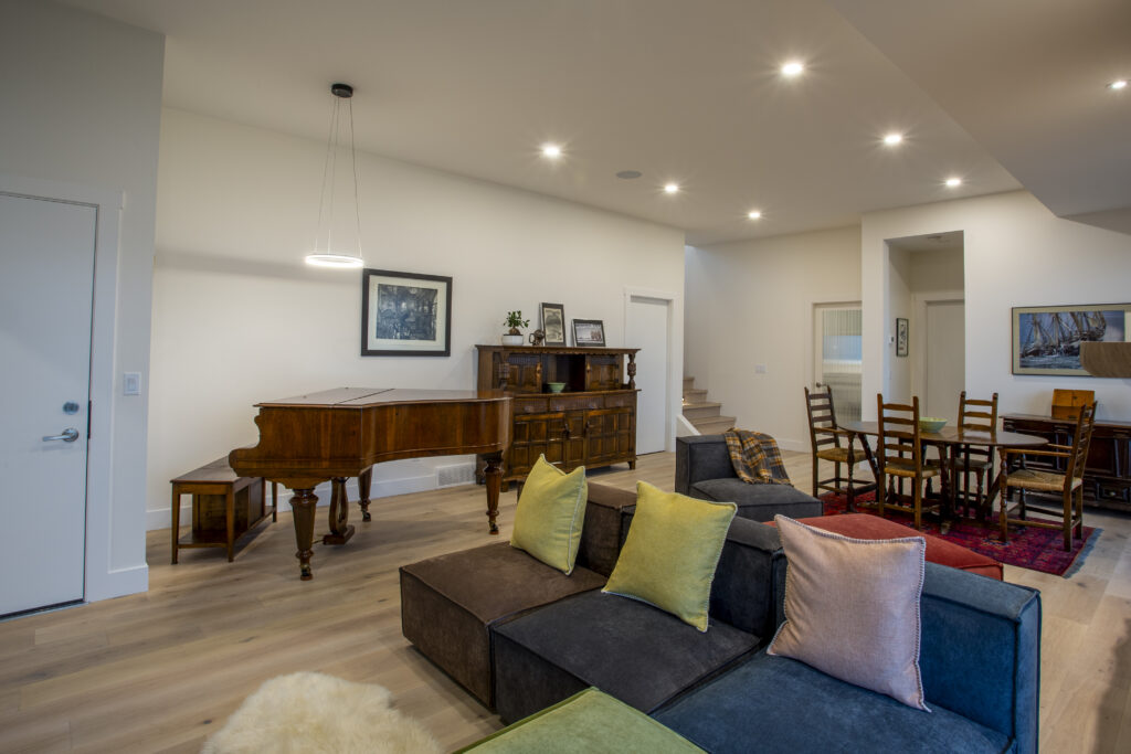 Living area with a grand piano, sectional sofa, and modern decor.