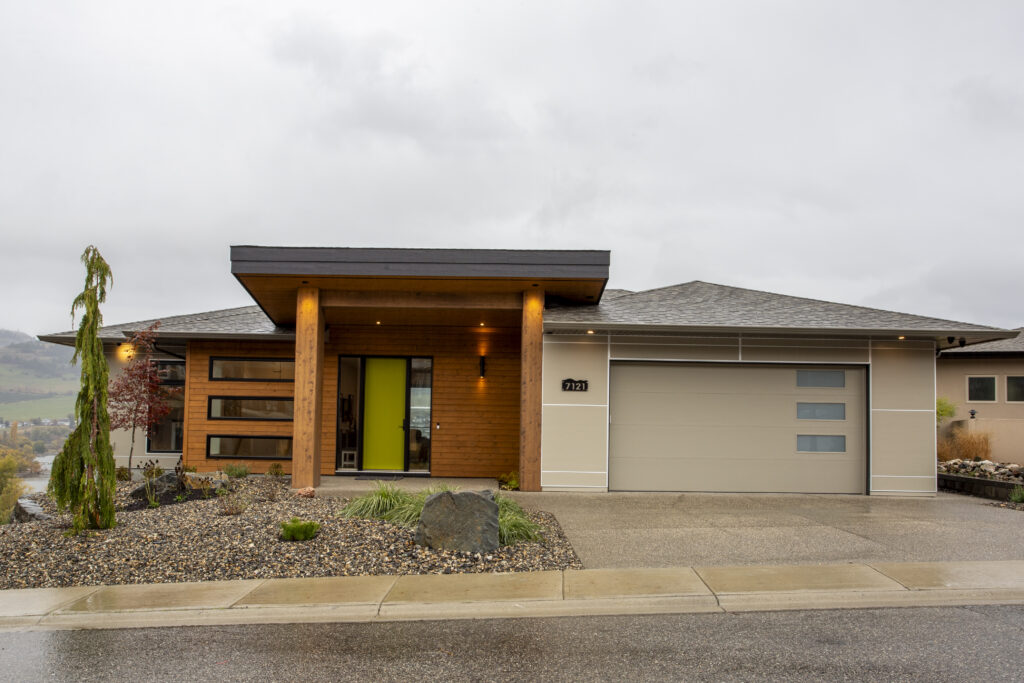 Exterior view of a modern home with a vibrant green front door and landscaped yard.