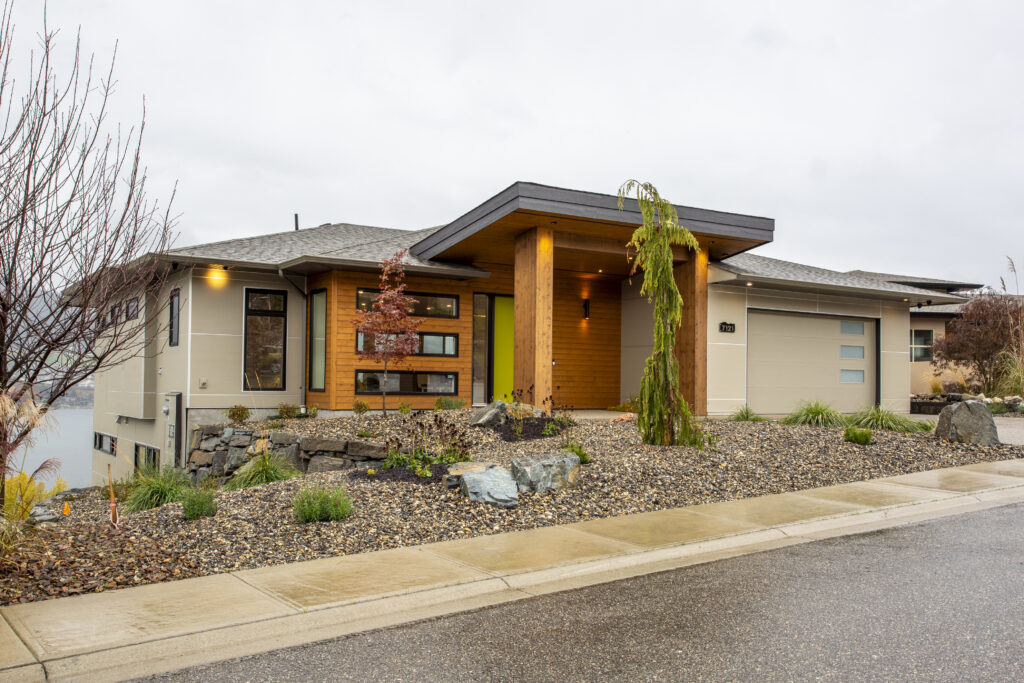 Exterior view of a modern home with a vibrant green front door and landscaped yard.