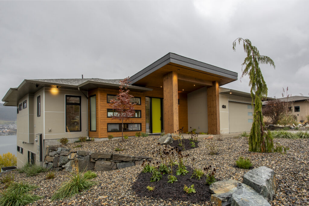 Exterior view of a modern home with a vibrant green front door and landscaped yard.