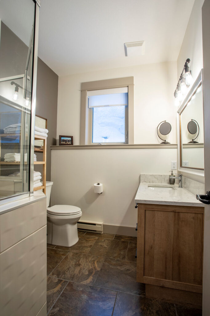Modern bathroom vanity with a marble countertop, framed mirror, and soft lighting in a Keith Construction home renovation.