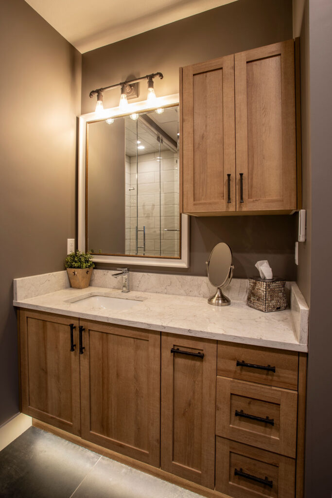Bathroom with wooden cabinetry, marble countertop, and large mirror.