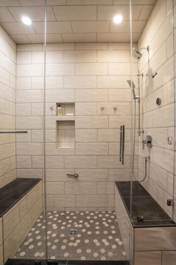 Spacious shower with tiled walls, built-in benches, and glass door.
