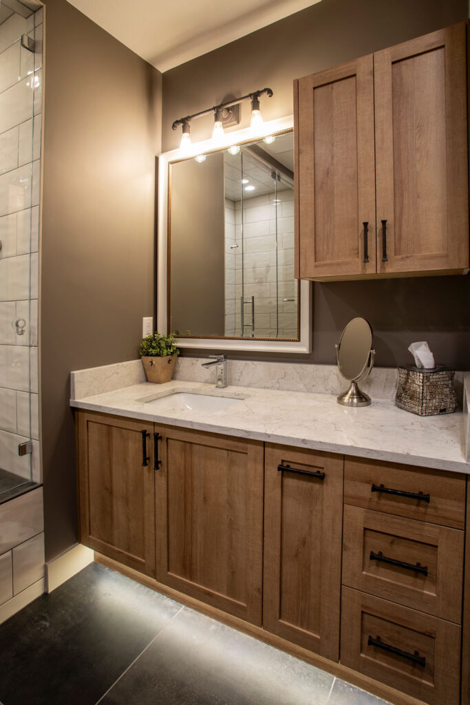 Bathroom with wooden cabinetry, marble countertop, and large mirror.