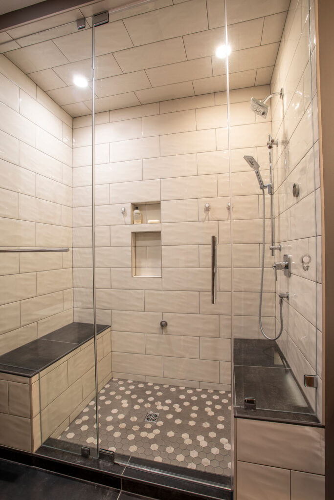 Spacious shower with tiled walls, built-in benches, and glass door.