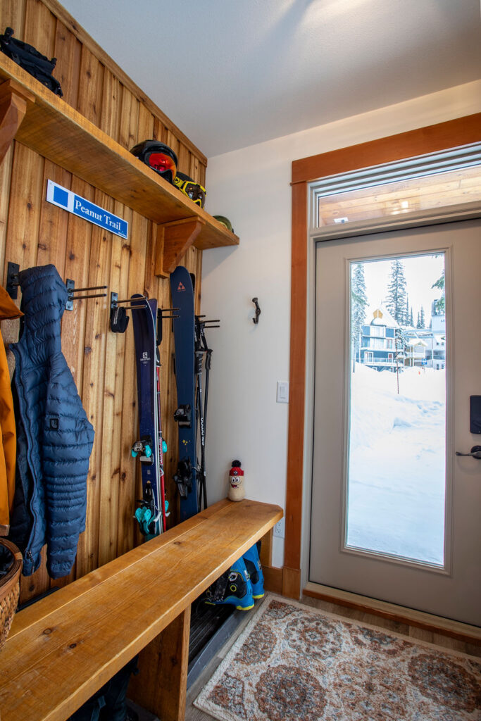 Ski entryway with wooden walls, hooks for jackets, and a bench for storing ski gear.