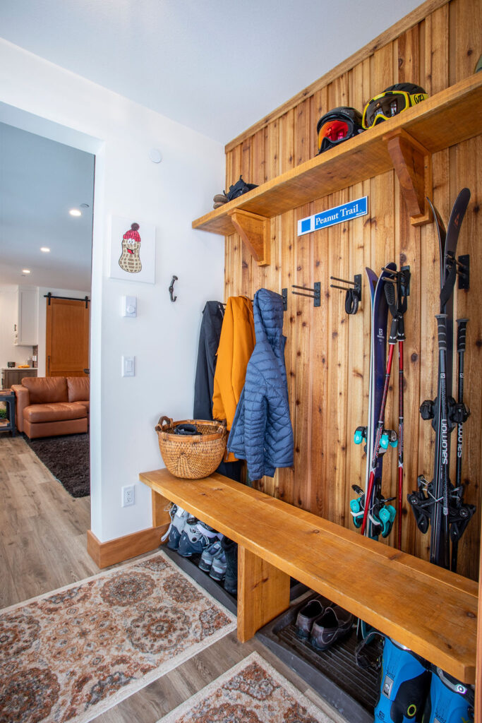 Entryway with a wooden storage area, hooks for ski equipment, and a basket for accessories.