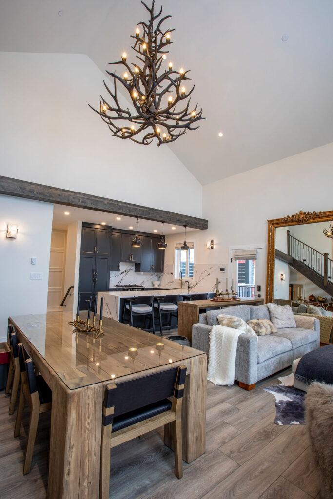 Rustic-inspired dining area with a wood table, black leather chairs, and a dramatic antler chandelier in a custom home by Keith Construction.