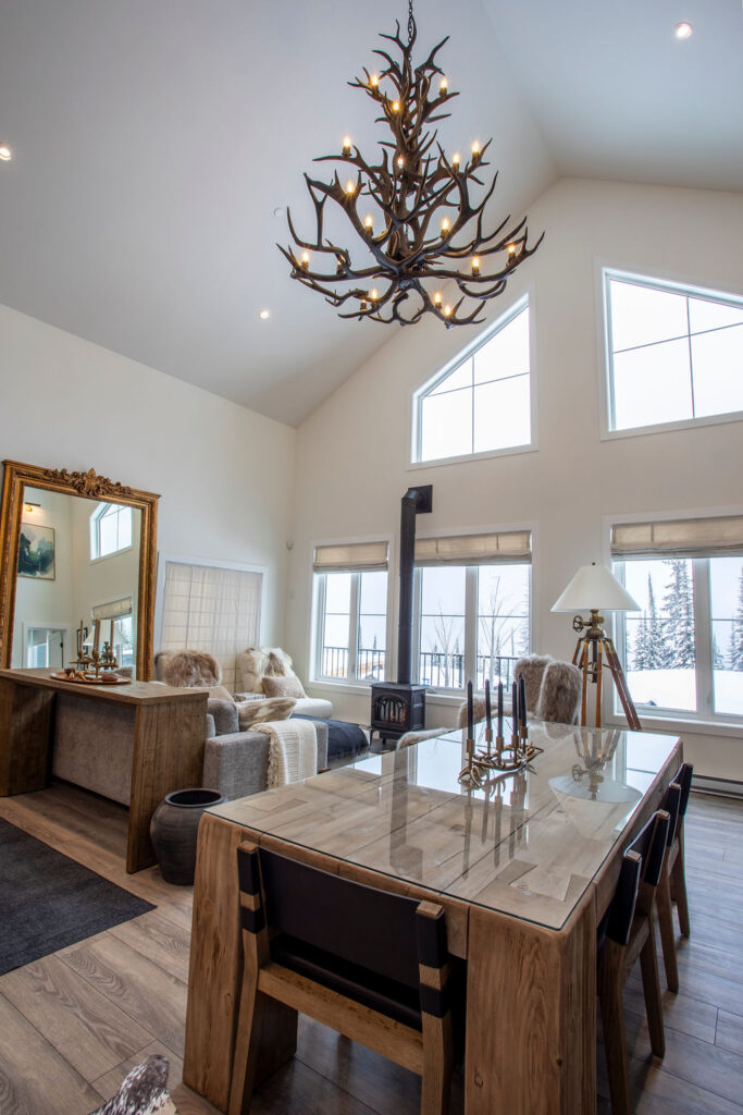 Image of the dining table and living area with large windows and natural light.