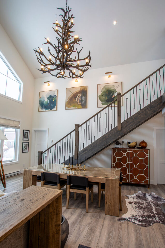 Image of a high-ceiling living area with modern decor and large artwork above the stairs.