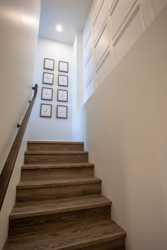 Staircase with wooden steps and a handrail, decorated with framed pictures on the wall.