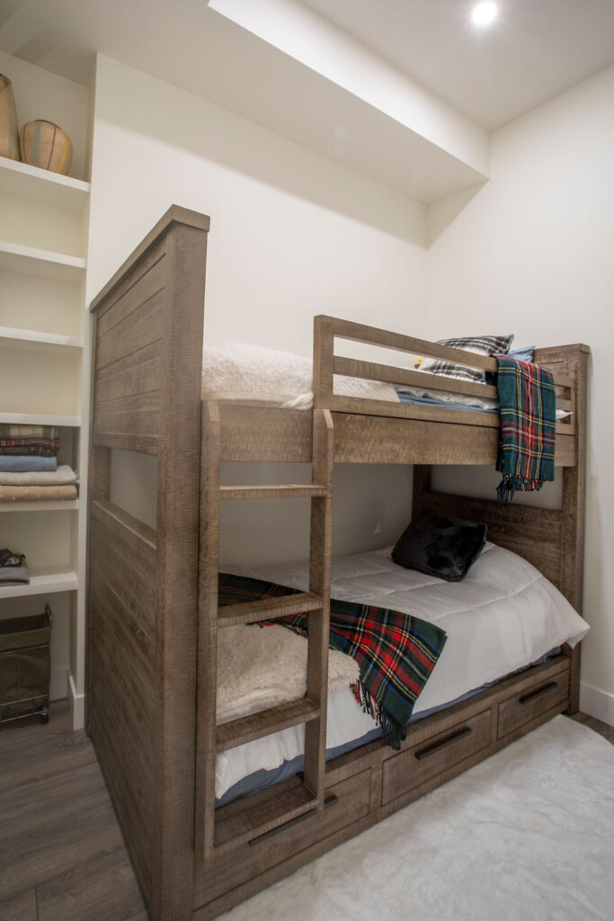 Bunk bedroom featuring wooden bunk beds with plaid blankets and built-in storage.