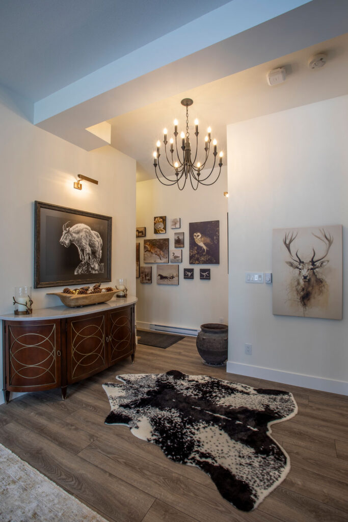 Hallway entrance decorated with artwork and a chandelier, featuring a rustic console table and cowhide rug.