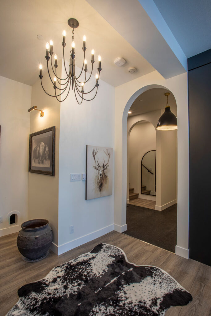 Entryway area featuring a chandelier, artwork, and a cowhide rug on wooden floors.