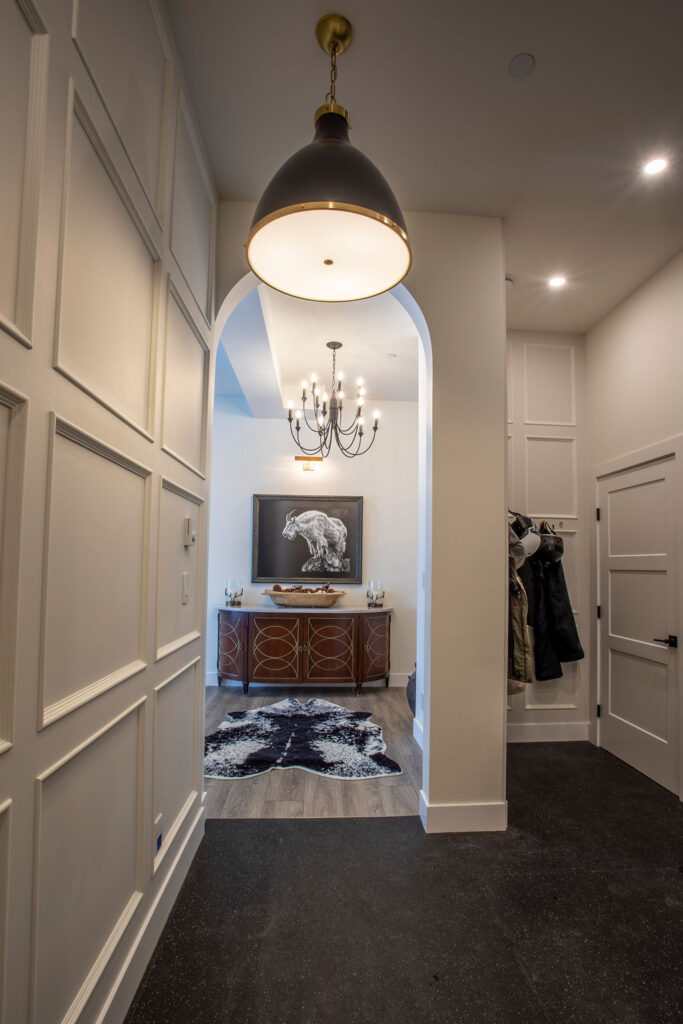 Hallway with an arched doorway leading to a room with a console table and chandelier.