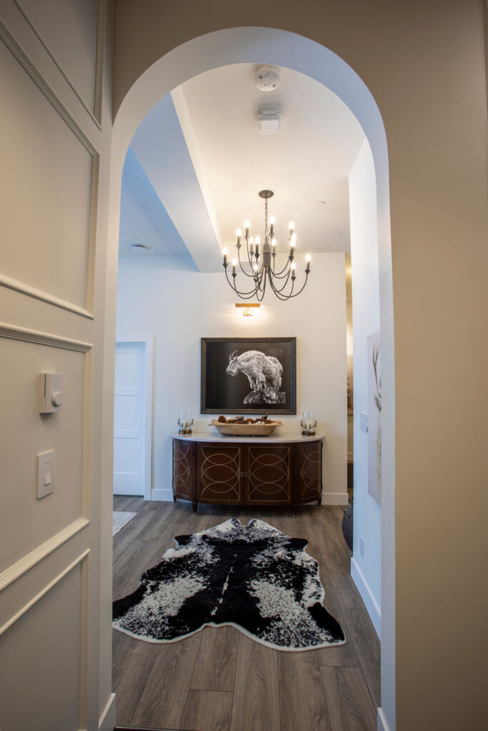 Hallway with an arched doorway leading to a room with a console table and chandelier.