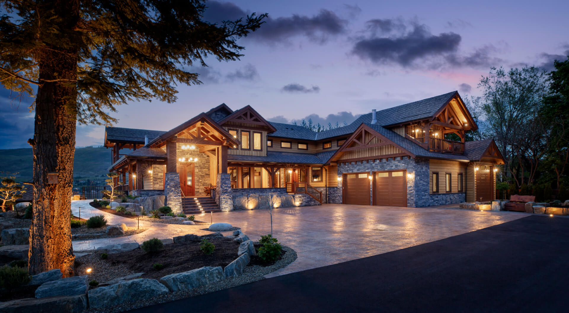 Modern custom home with wood and dark metal siding, large windows, and a spacious driveway, built by Keith Construction in Coldstream, BC.