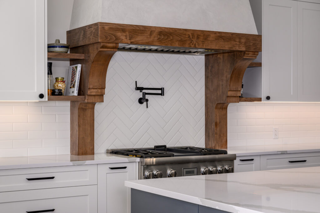 Rustic kitchen design with a custom wood range hood and white subway tile backsplash.